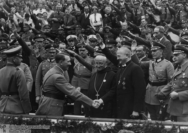 Hitler begrüßt Reichsbischof Ludwig Müller und Abt Albanus Schachleitner auf der Ehrentribüne des „Reichsparteitag der Einheit und Stärke” (4.-10. September 1934)